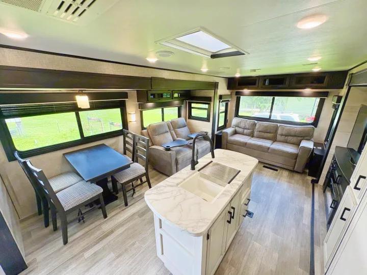 Spacious RV rental with a modern interior. Features a kitchen island, living room with recliners, and dining area on light wood floors.. Jayco Jay Flight 2022