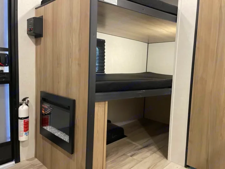 RV rental interior: Bunk beds, an electric fireplace, and fire extinguisher provide comfort & safety in this cozy space.. Keystone RV Coleman 13B 2026