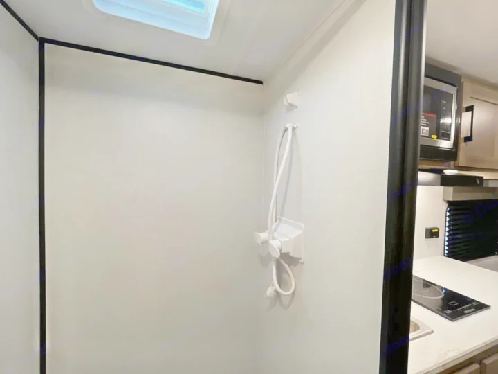 RV rental interior: A compact shower area with a skylight, next to a kitchenette featuring a microwave and stovetop.. Keystone RV Coleman 13B 2026