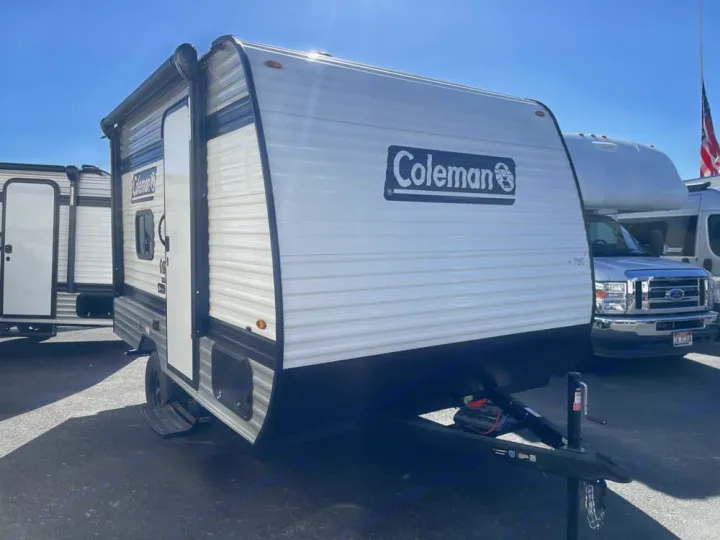 Coleman travel trailer available for rv rental. This compact white & black RV is parked outdoors, ready for your road trip.. Keystone RV Coleman 13B 2026