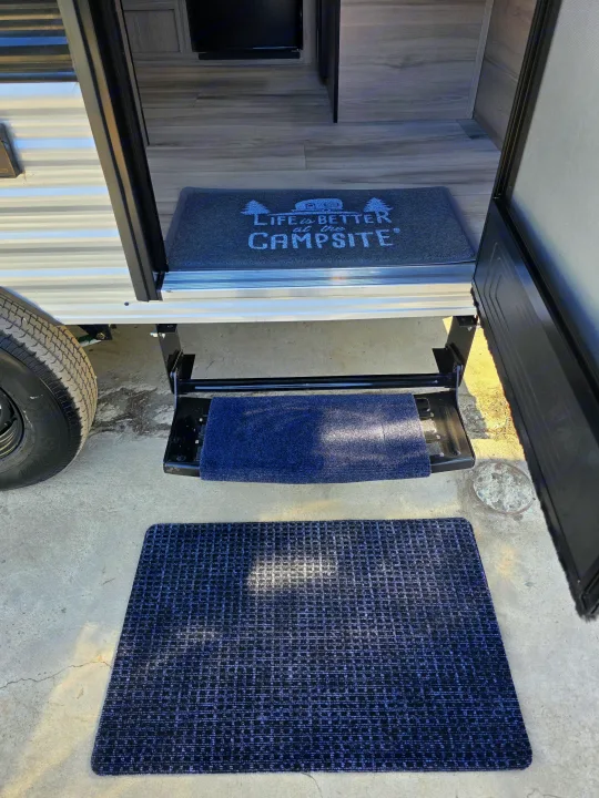 RV rental entrance with three protective mats, including a "Campsite" mat, leading from outside concrete to the interior floor.. Keystone RV Coleman 13B 2026