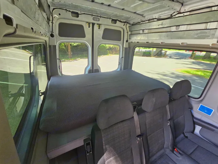RV rental interior: spacious camper van with bed & 3 passenger seats. View from inside at parking lot.. Mercedes-Benz Sprinter 2016