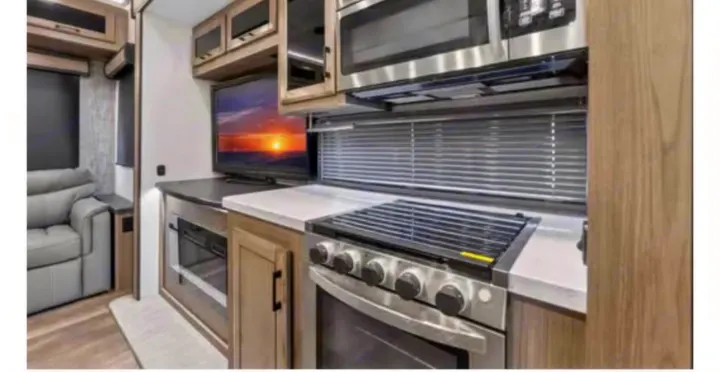 Spacious RV rental features a modern kitchen with stove, microwave, and TV, plus comfy seating for your travels.. Crossroads RV Cameo 2022