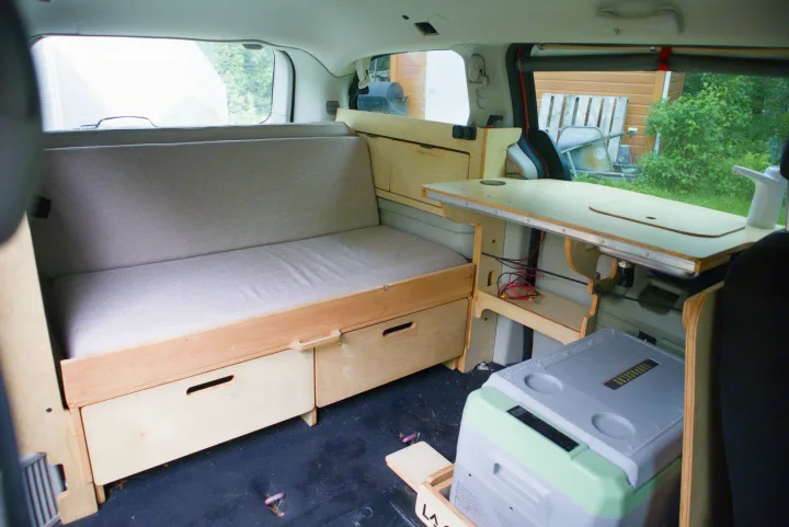 RV rental camper interior with comfy bench seating, wooden storage drawers, and a built-in table with a faucet.. Dodge Grand Caravan 2015