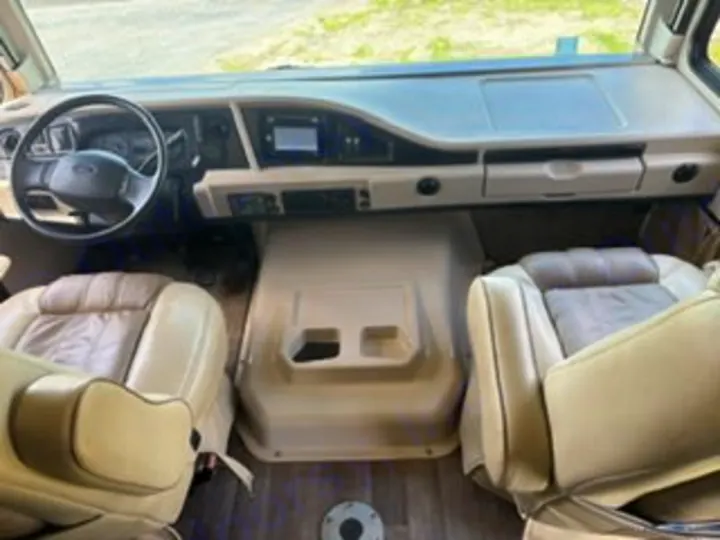 Interior view of an RV rental's front cabin: light-colored captain's chairs, steering wheel, and dashboard, ready for your road trip.. Fleetwood FLAIR 2020