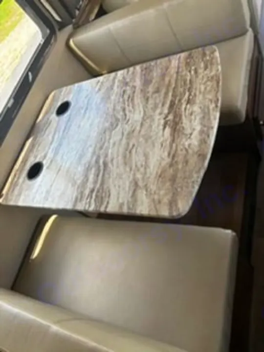 This RV rental features a cozy dinette with light-colored benches and a patterned table with cup holders, ideal for meals & relaxation.. Fleetwood FLAIR 2020