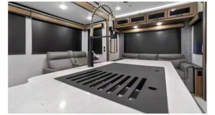 This modern RV rental features a stylish kitchen island with a black faucet, gray seating, and blackout blinds.. Crossroads RV Cameo 2022