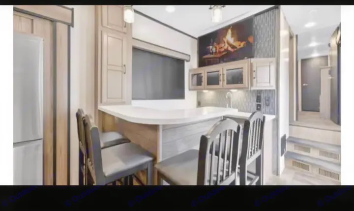 RV rental: Modern kitchen with bar seating, white counter, dark stools, and fridge. Steps to rear area. Well-lit interior.. Crossroads RV Cameo 2022