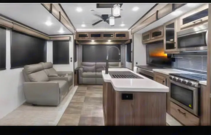 Inside a modern rv rental: a cozy living area with sofas, a kitchen island, and full appliances for comfortable travel.. Crossroads RV Cameo 2022