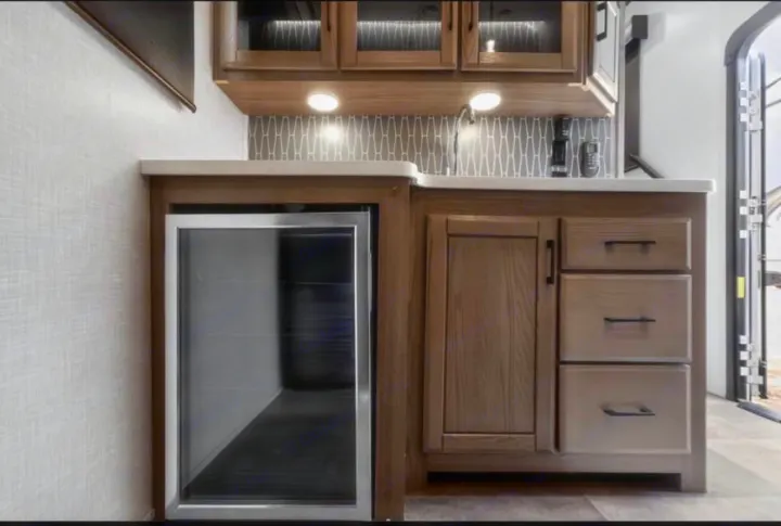 Modern rv rental kitchen with built-in beverage cooler, sink, and stylish wood cabinets. Perfect for on-the-go meals.. Crossroads RV Cameo 2022
