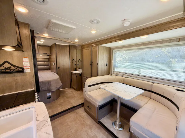 RV rental interior features a dining booth, kitchen sink, and bedroom. Bright, modern living space.. Coachmen RV Prism Select 24CB 2021