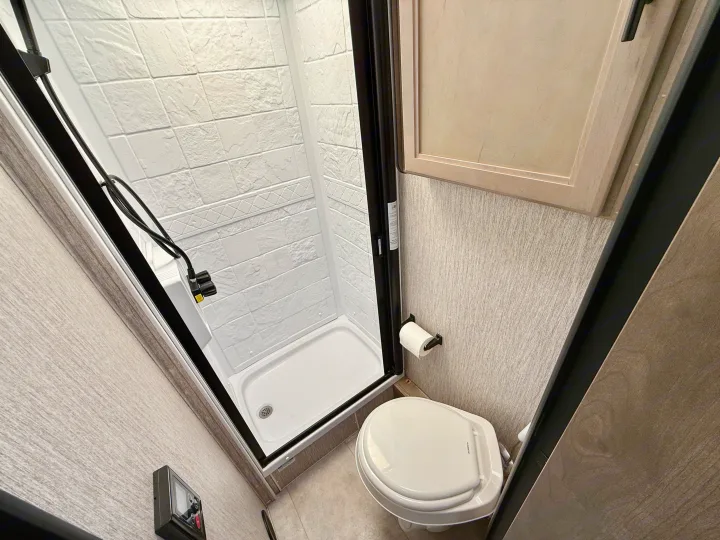 Compact rv rental bathroom featuring a bright shower stall with white textured walls and a Dometic toilet.. Coachmen RV Prism Select 24CB 2021