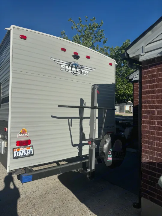 Rear of a gray Shasta travel trailer (rv rental) with a Utah license plate, Castle Country RV branding, and IKON bike rack.. Forest River Shasta 2021
