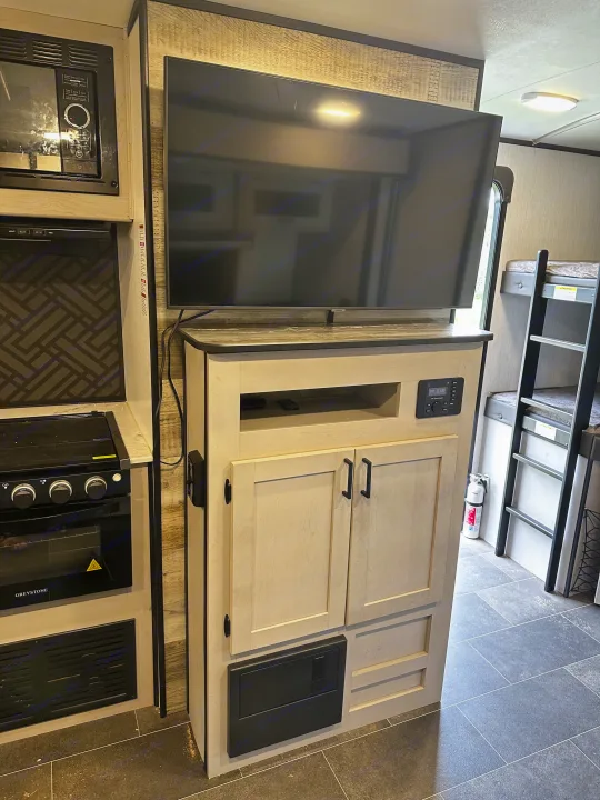 Modern RV rental interior featuring kitchen, entertainment center with TV, and bunk beds, ideal for a comfortable trip.. Heartland RVs Mallard 2022