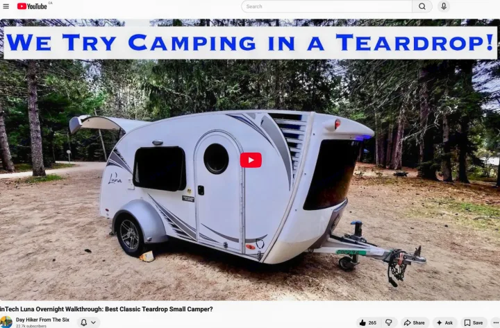 This white InTech Luna teardrop camper, ideal for an RV rental or camping trip, is shown in a forest. The video explores small campers.. InTech RV Luna 2018