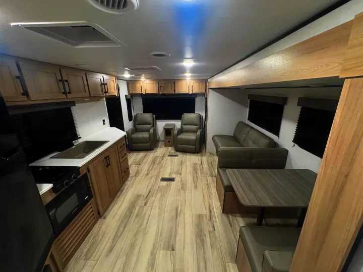 Spacious, modern rv rental interior with full kitchen, living area (recliners, sofa), and dining booth. Light wood flooring.. Keystone RV Other 2026