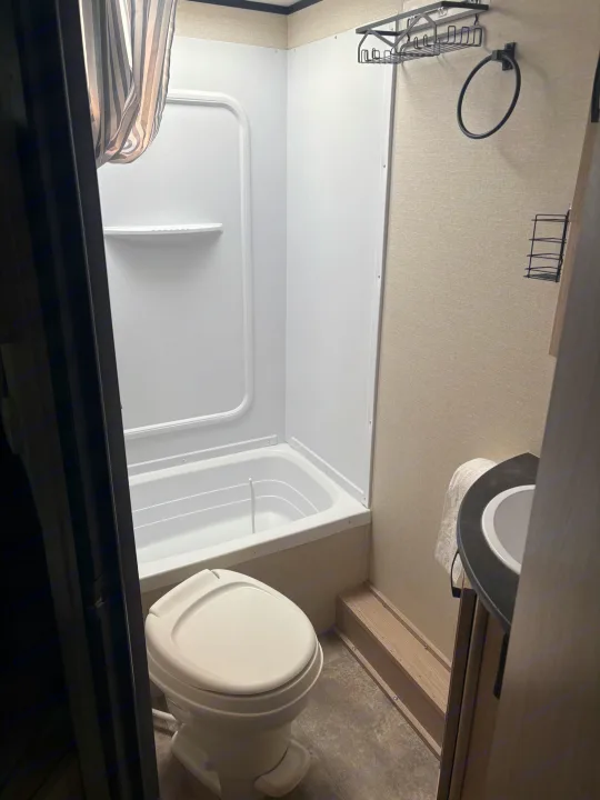 Experience comfort in this RV rental bathroom featuring a shower, toilet, and sink, designed for compact travel.. Coachmen Apex 2022