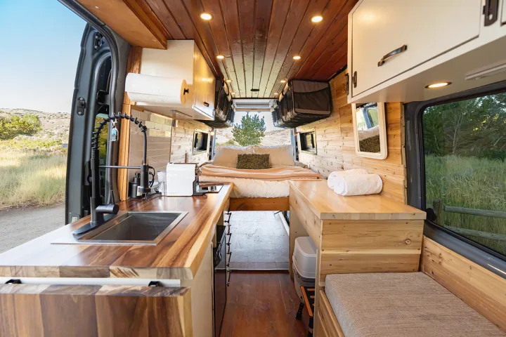 Stylish RV rental interior: wood-paneled camper van with kitchen, bed, and seating for road trip adventures.. MERCEDES-BENZ SPRINTER 2500 170 WB 2022