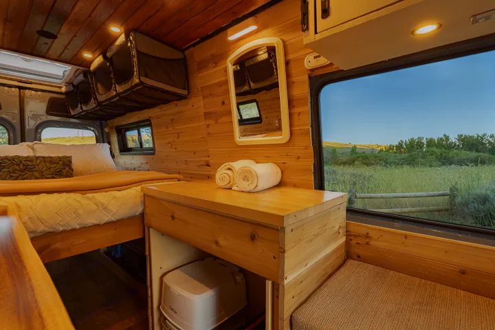 Experience nature in this cozy RV rental with wood interior, comfy bed, storage, portable toilet, and scenic window views.. MERCEDES-BENZ SPRINTER 2500 170 WB 2022