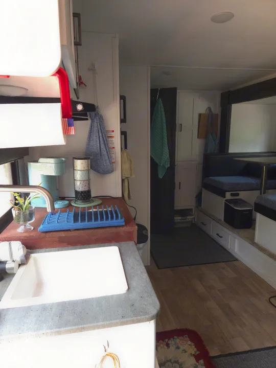 Compact RV rental interior: kitchen with sink, coffee maker, dining area with booth seating & ice maker. Cozy, mobile living.. Keystone RV Hideout 2022