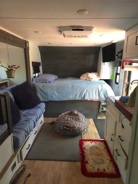 Comfortable rv rental interior: blue bed, sofa with drawers, compact kitchen counter, and bean bag chair for travel.. Keystone RV Hideout 2022