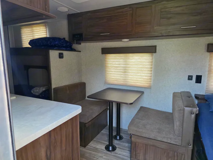 RV rental interior featuring a dinette table with bench seating, bunk beds, and overhead cabinets for storage.. Forest River Cherokee Wolf Pup 2018