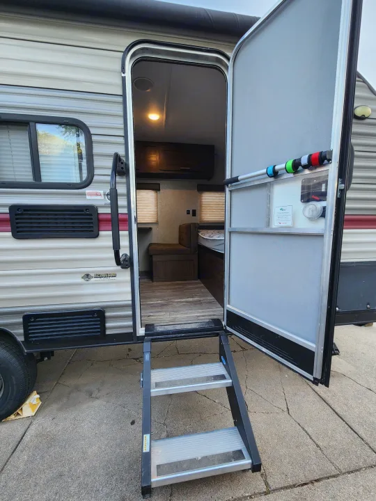 RV rental showing an open entry door with extended steps, revealing a glimpse of the interior, ready for camping travel.. Forest River Cherokee Wolf Pup 2018