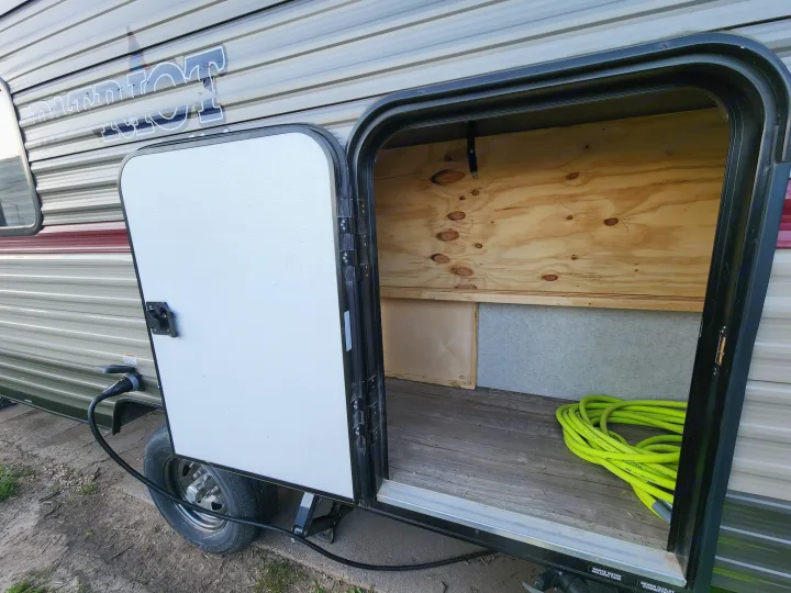 This RV rental offers ample storage. The open compartment reveals a coiled green hose & wooden interior for your gear.. Forest River Cherokee Wolf Pup 2018
