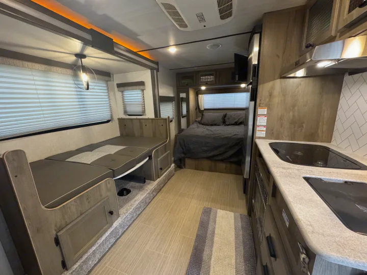 Modern RV rental interior with a cozy bedroom, adaptable dinette, and sleek kitchenette. Perfect for travel adventures.. Forest River Surveyor Legend 2021