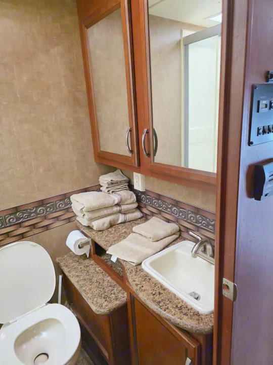 Compact RV rental bathroom with toilet, sink, shower, and fresh towels. Essential amenities for your trip.. Thor Four Winds 2015