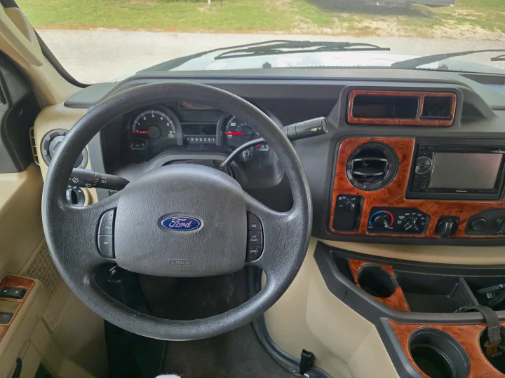 A Ford RV rental interior: dashboard with steering wheel, instruments, climate controls, and Pioneer stereo setup.. Thor Four Winds 2015