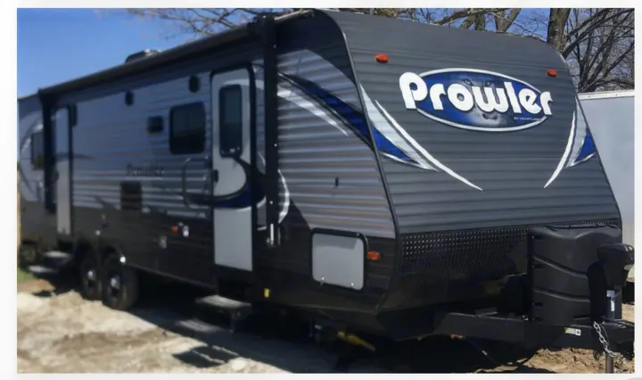 Prowler travel trailer RV rental: a gray and blue recreational vehicle with an awning, ready for your trip.. Heartland Prowler 2019
