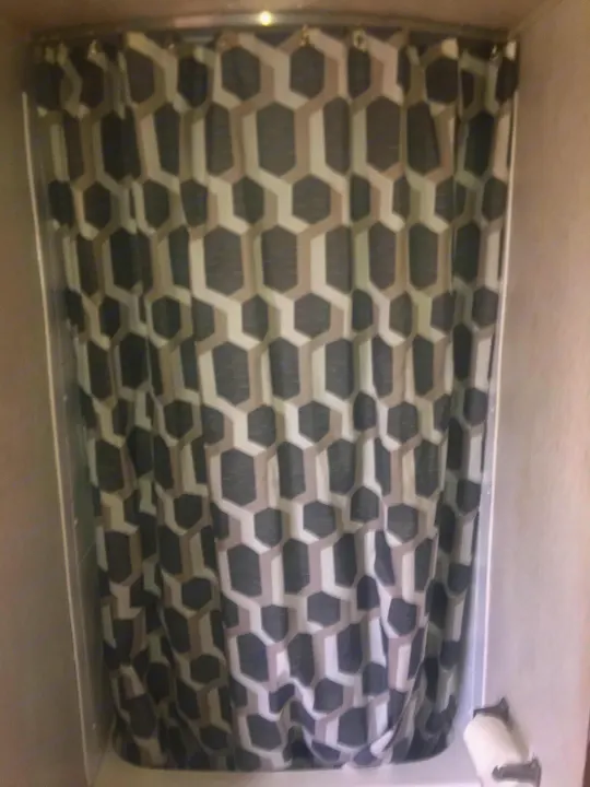Grey and white geometric shower curtain in an RV rental bathroom. Offers a modern look and privacy.. Heartland Prowler 2019