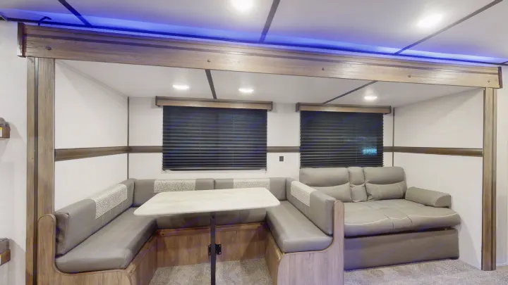 Spacious RV rental interior with a versatile U-shaped dinette, comfy sofa, and ambient blue lighting.. Crossroads Zinger 2022