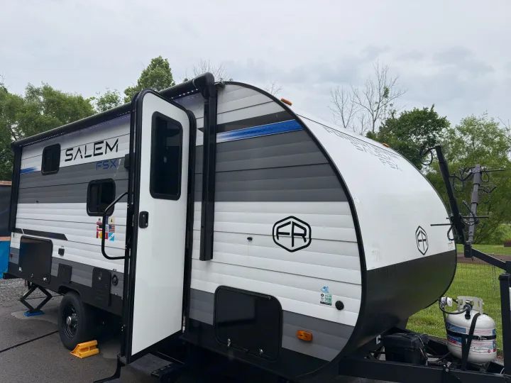 Salem FSX travel trailer rv rental, white and grey, features an open door, awning, and bike rack, perfect for your camping adventures.. Forest River Salem FSX 2025