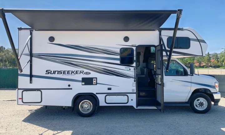 White Forest River Sunseeker Class C **RV rental** with extended awning & open door. Ready for your adventure!. Forest River Sunseeker LE 2023