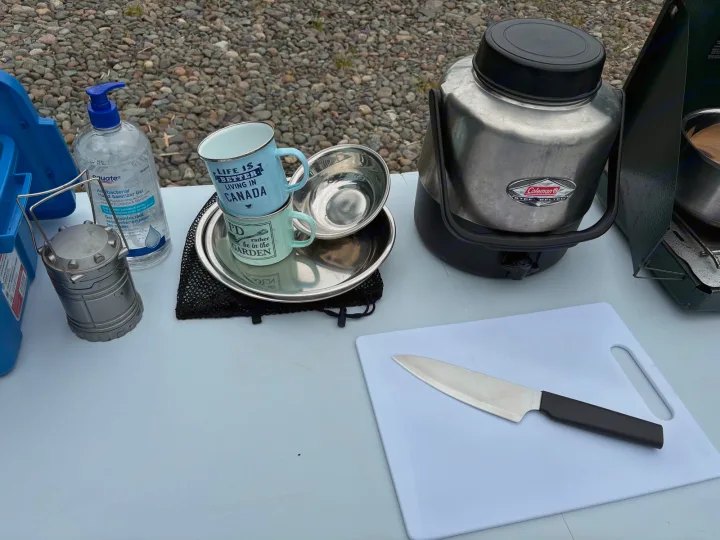 RV rental essentials: hand sanitizer, "Canada" mugs, cooler, knife & cutting board for outdoor cooking on gravel.. chevy uplander 2006