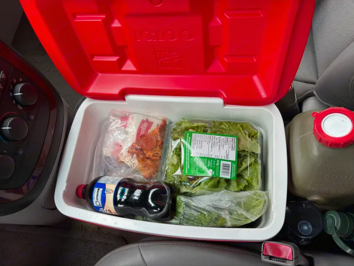 Open Igloo cooler in an rv rental, packed with lettuce, pizza toppings, soda, and a water jug, ready for a trip.. chevy uplander 2006