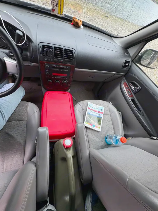 Car interior prepared for a road trip: red cooler, gas can, and travel guide. All set for adventure, perhaps in an RV rental!. chevy uplander 2006