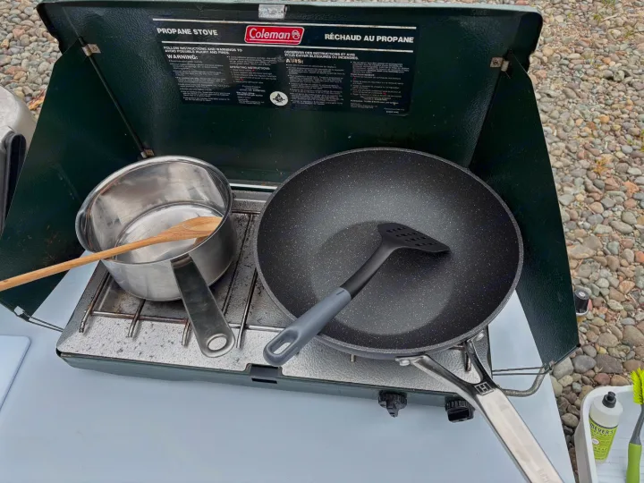 Outdoor cooking setup on a Coleman propane stove, with pans and utensils, ideal for your RV rental adventure.. chevy uplander 2006