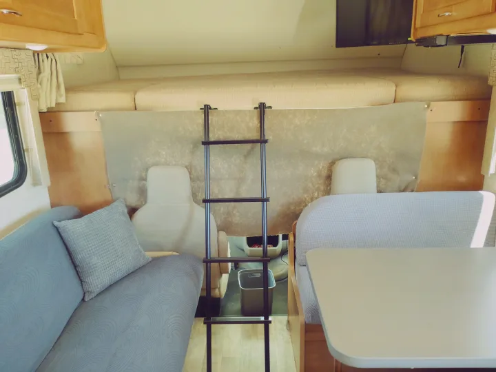 Inside an rv rental: sofa, dining booth, overhead bunk bed with ladder.. Winnebago Minnie Winnie 2017