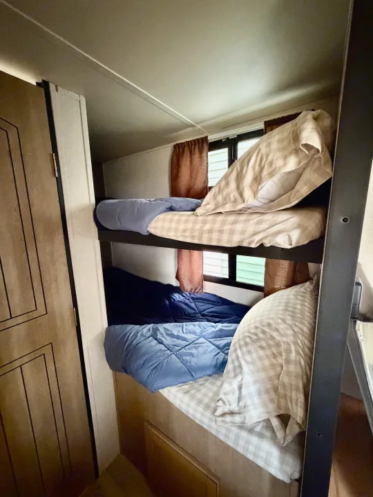 RV rental bunk beds: comfortable sleeping space with checkered and blue bedding, ideal for family trips.. Palomino Real Lite Mini 2017