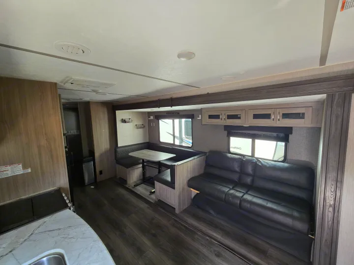 RV rental interior: inviting dinette, plush sofa, and a functional kitchen. Modern wood-look design for comfortable travel.. Coachmen Freedom Express 2022