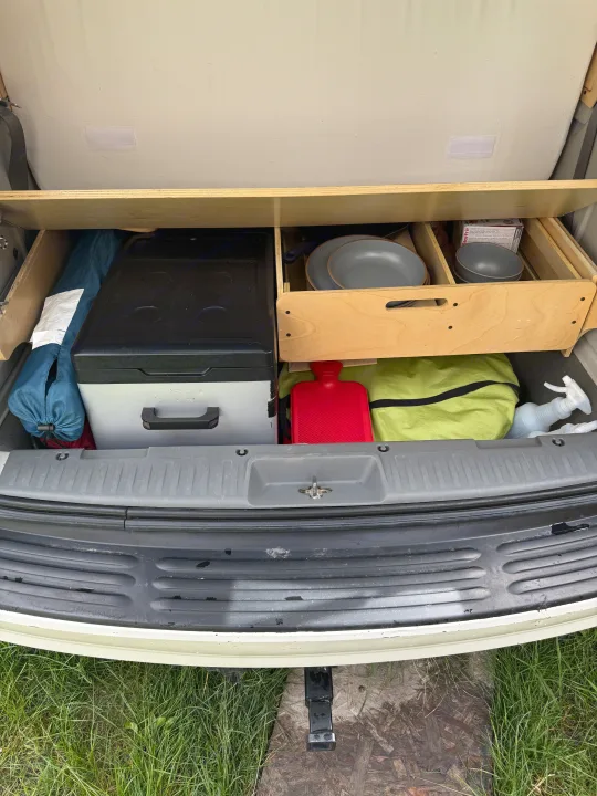 RV rental storage: Cooler, cookware, and camping gear neatly organized in the vehicle's rear compartment.. Volkswagen Routan 2011