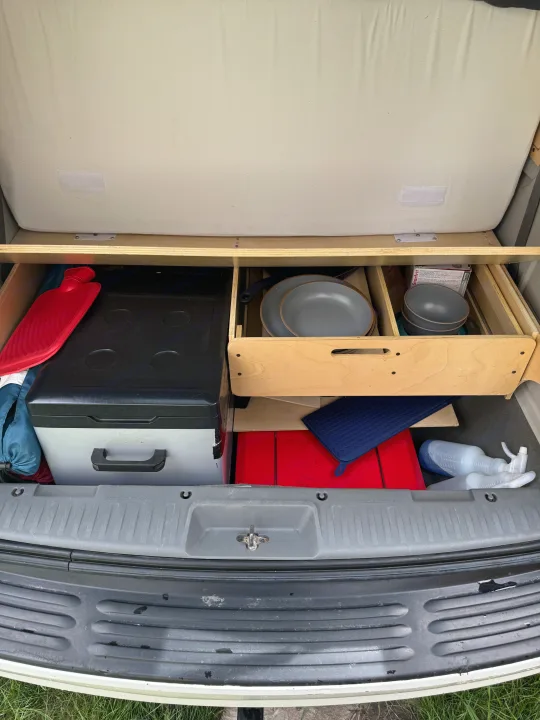 RV rental: Compact camper storage with cooler, cooking essentials, and supplies neatly stored under the bed.. Volkswagen Routan 2011