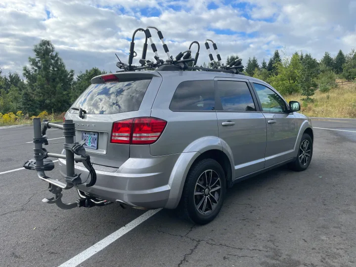 Grey SUV with roof kayak carriers & a rear bike rack, offering versatile outdoor sports travel. A flexible choice over an RV rental.. Dodge Journey 2017