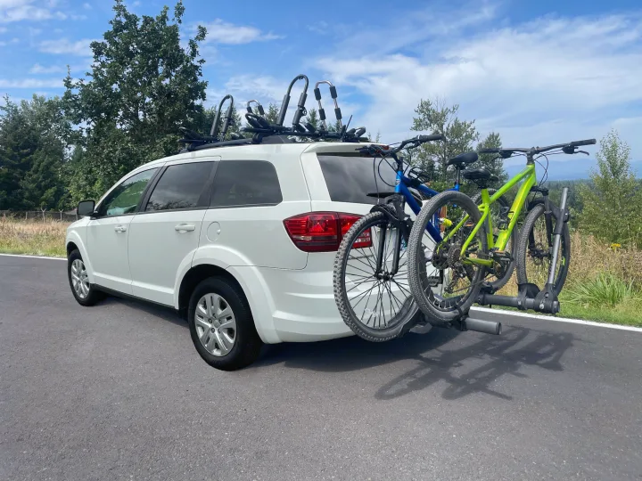 White car, perfect RV rental complement, with roof racks & hitch rack carrying two mountain bikes for outdoor adventures.. Dodge Journey 2016
