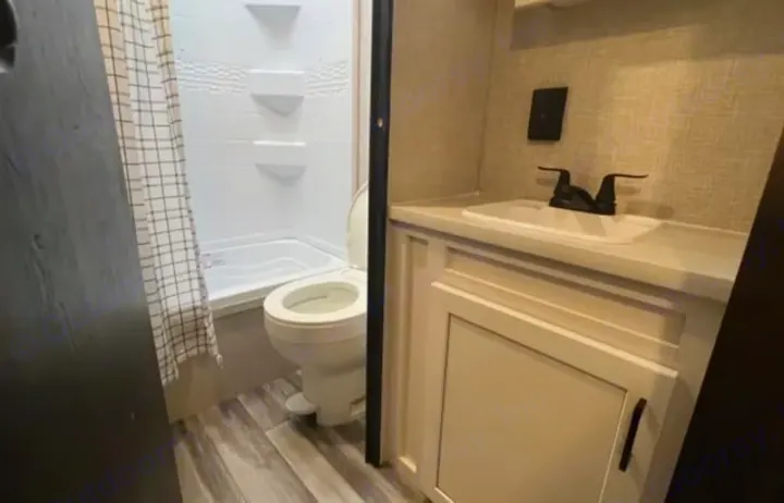 Compact, modern RV rental bathroom: features a toilet, shower, and vanity sink with a dark faucet. Efficient and clean design for travel.. Jayco Jay Flight 2024