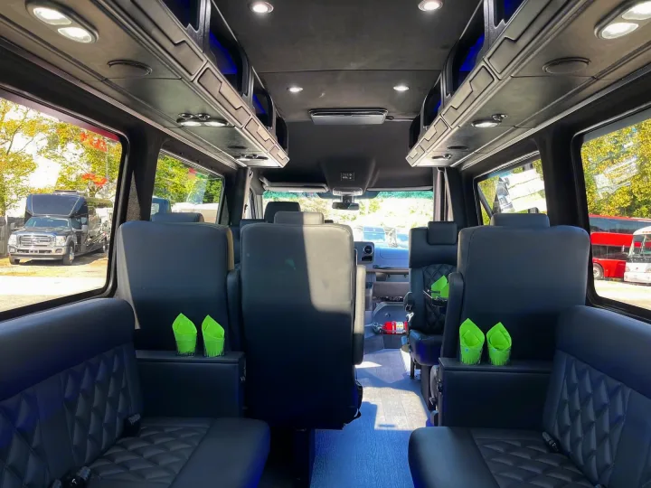 View inside a luxurious RV rental, featuring plush black leather seating, overhead storage with blue accent lights, and bright ceiling lights.. Forest River 2025