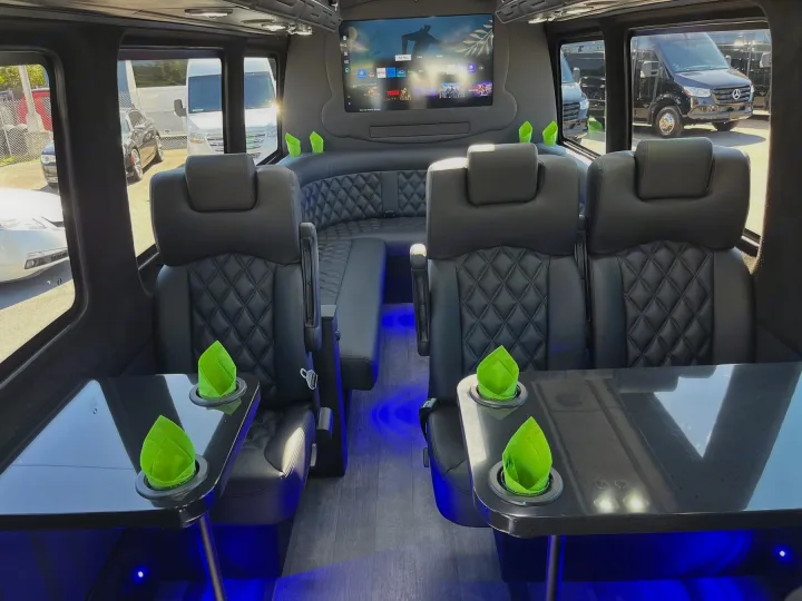Luxury RV rental interior: spacious seating, large TV, tables with bright green accents, and ambient blue lighting.. Forest River 2025